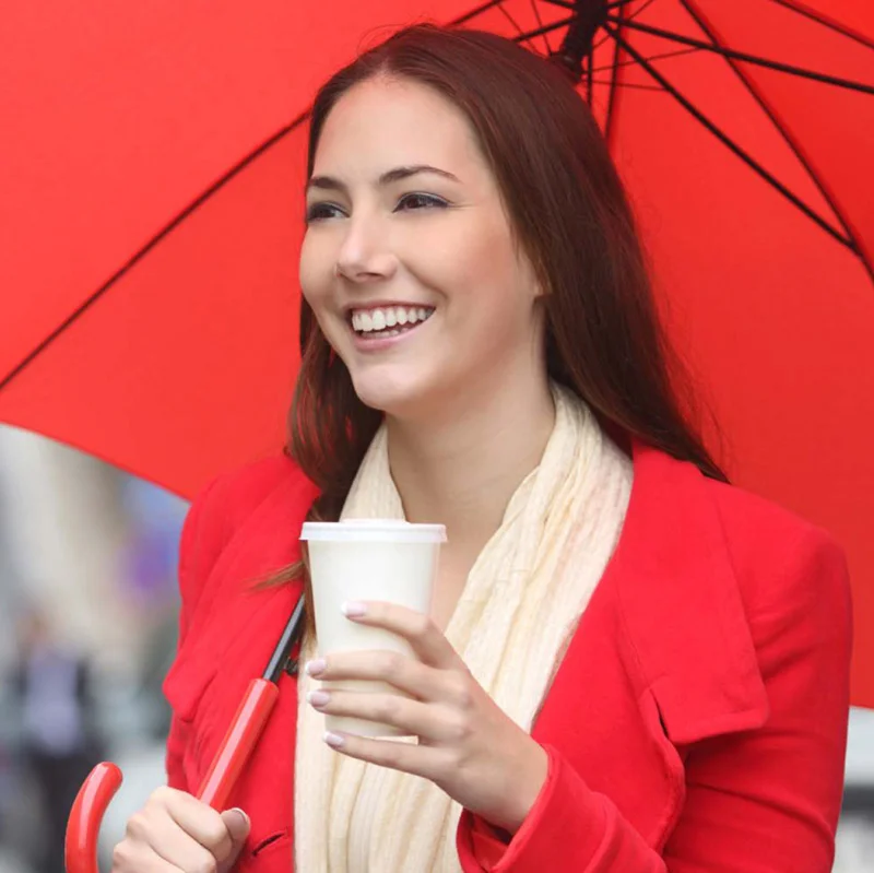 Woman holding a coffee and an umbrella
