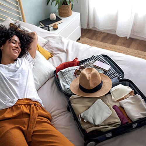 Additional Image 5 - a woman lying on a bed with a suitcase