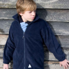 a boy standing in front of a wooden wall