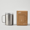 a silver mug next to a brown box