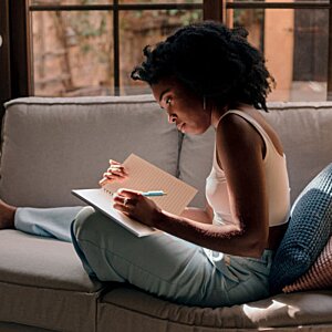 Additional Image 2 - a woman sitting on a couch writing on a paper