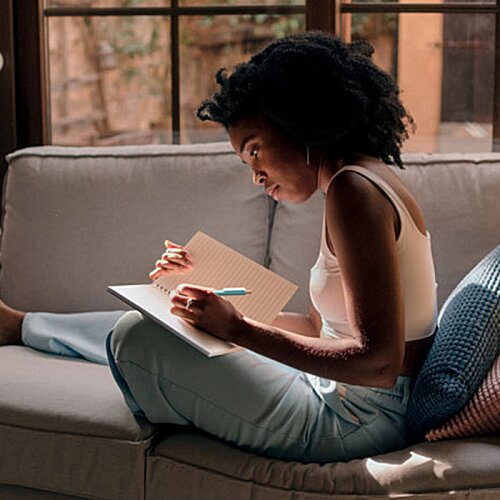 Additional Image 2 - a woman sitting on a couch writing on a paper