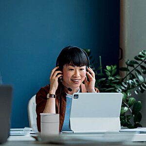 Additional Image 8 - a person sitting at a desk with a laptop and headset