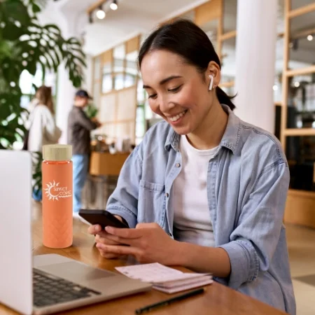 Smiling person sitting at a desk with a reusable water bottle.